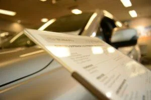 Detailansicht eines Fahrzeugpreisschilds in einem modernen Autohaus, betont die Bedeutung von Cybersicherheit und ISO 27001 Zertifizierung für Autohändler.