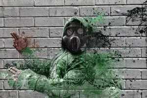 Graffiti artwork depicting a figure in a green hoodie and gas mask, set against a gray brick wall, emphasizing themes of safety and protection relevant to certification discussions.