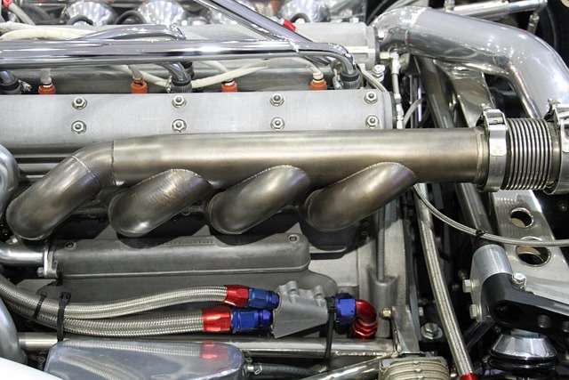 Detailansicht eines Automobilmotors mit verchromtem Abgaskrümmer und Hochleistungsleitungen, relevant für ISO-Zertifizierungen und Qualitätsstandards in der Automobilindustrie.