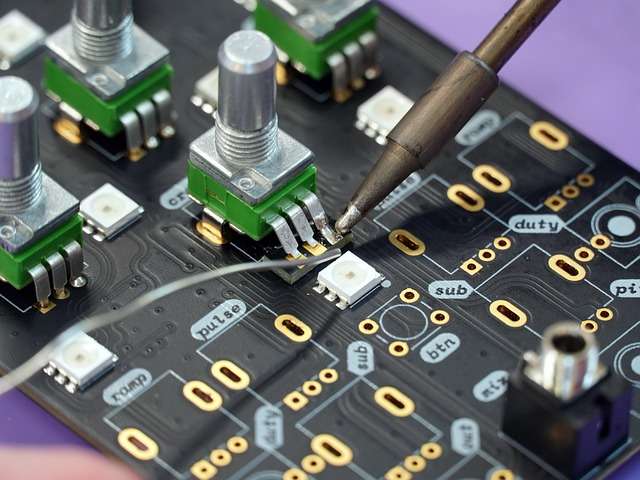 Löten von Komponenten auf einer Leiterplatte mit Potentiometern, relevante Tätigkeit in der Automobilindustrie zur Sicherstellung von Qualitätsstandards und ISO-Zertifizierungen.